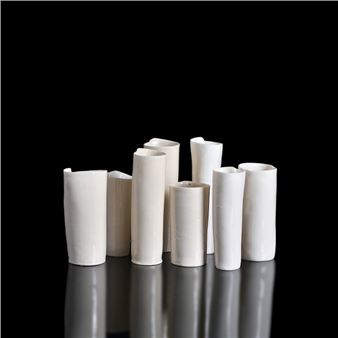 A minimalist arrangement of white ceramic vessels against a stark black background.