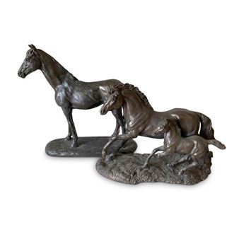 A bronze sculpture of a horse family with a standing adult, a prancing foal, and a foal on the ground.
