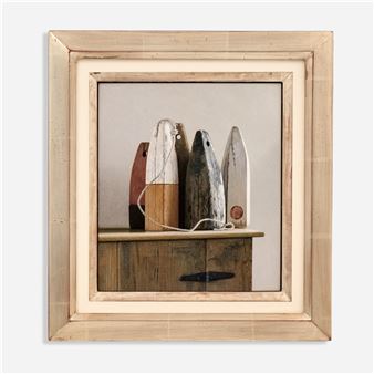 A framed still life of weathered wooden buoys resting on a rustic cabinet.