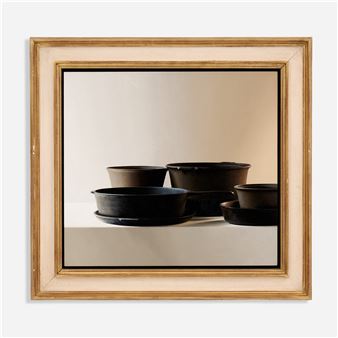 A framed still life of dark ceramic bowls on a white surface.