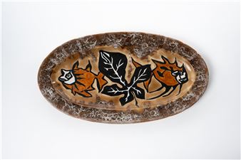 A ceramic platter featuring stylized animal heads and leaves.