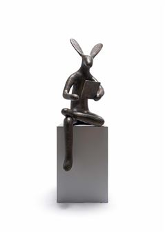A bronze rabbit-like figure reading a book while seated on a rectangular pedestal.