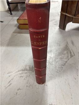 A close-up of a red hardcover book standing upright on a light surface.