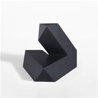 A minimalist black geometric sculpture resting on a white surface.
