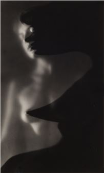 A dramatic black-and-white portrait of a figure in shadow with a hat, featuring soft lighting and deep contrast.