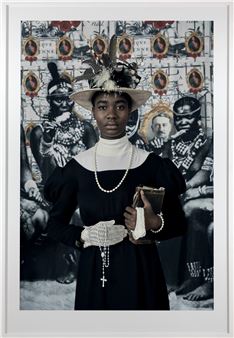 A portrait of a person in a dark dress and ornate hat standing before a collage of historical figures.