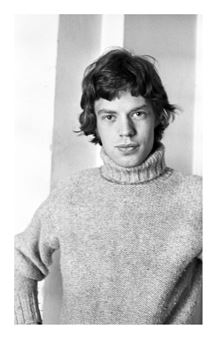 A black-and-white portrait of a young person with wavy hair wearing a textured turtleneck sweater.