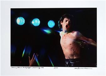 A shirtless figure performs passionately on stage under dramatic blue lighting.