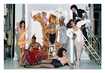 A dynamic fashion editorial featuring a group of models in elaborate costumes posing within a studio setting.