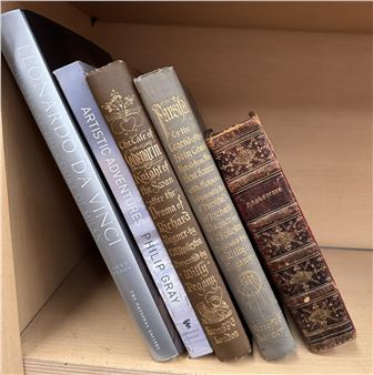 A collection of five vintage books leaning against a wooden shelf.