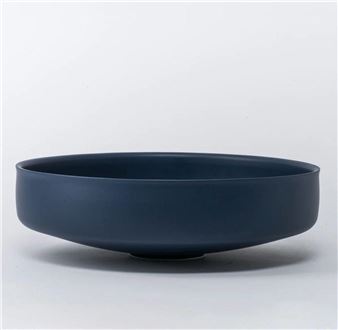A minimalist ceramic bowl with a matte navy finish and a shallow, wide rim.