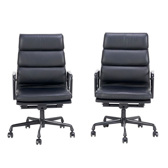 A pair of black leather office chairs with metal bases and wheels.