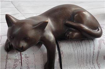 A bronze sculpture of a cat in a resting pose.