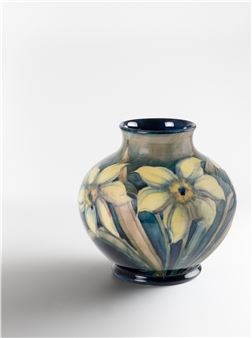 A ceramic vase featuring a floral pattern with yellow blossoms and green leaves against a neutral background.