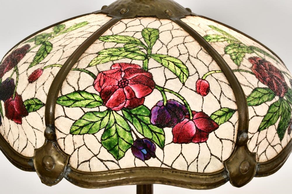 A tall floor lamp with a stained-glass floral shade and an ornate dark metal base.
