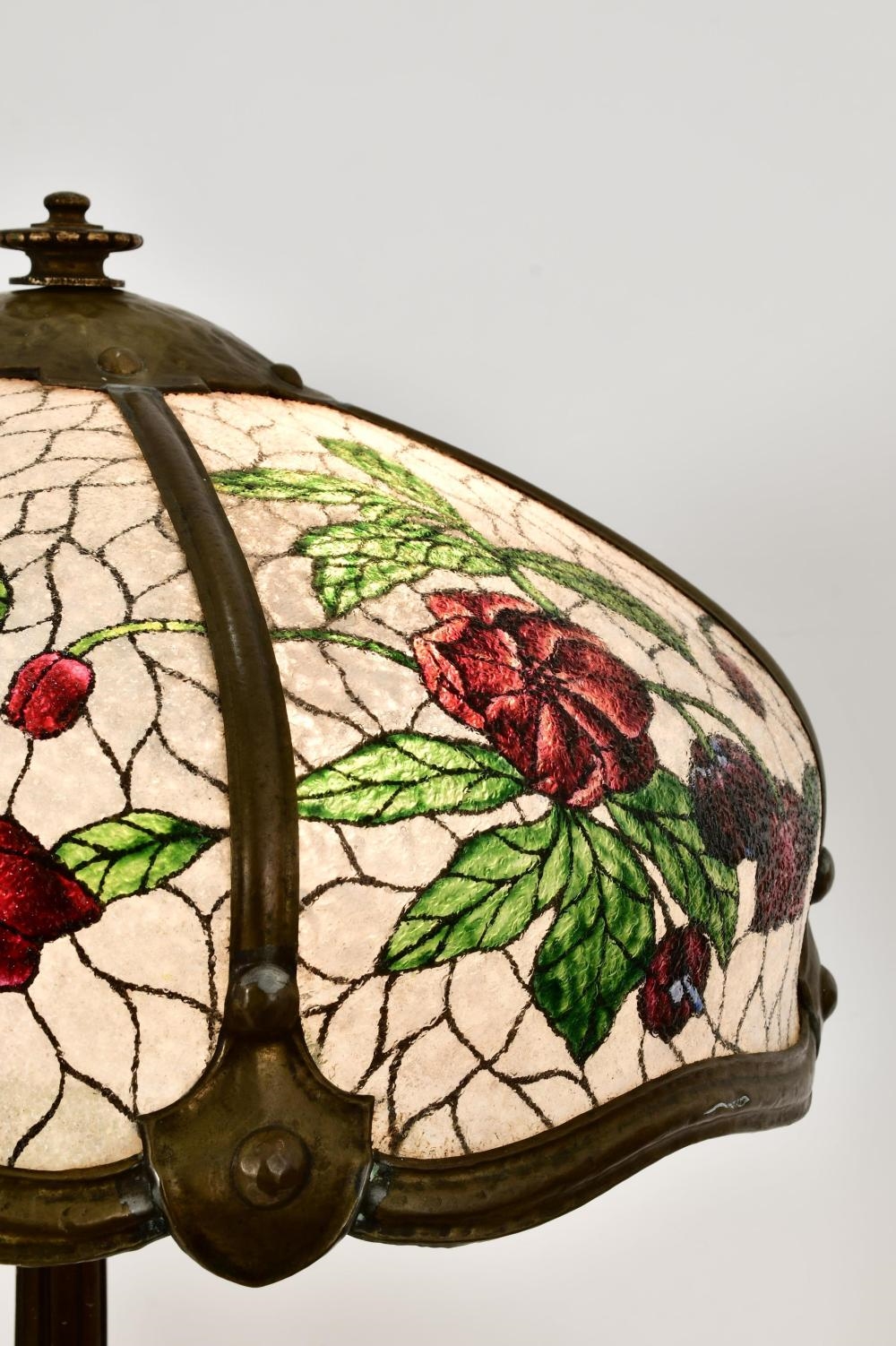 A tall floor lamp with a stained-glass floral shade and an ornate dark metal base.