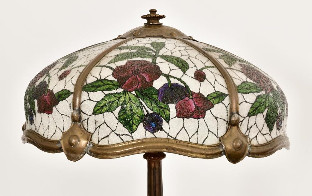 A tall floor lamp with a stained-glass floral shade and an ornate dark metal base.