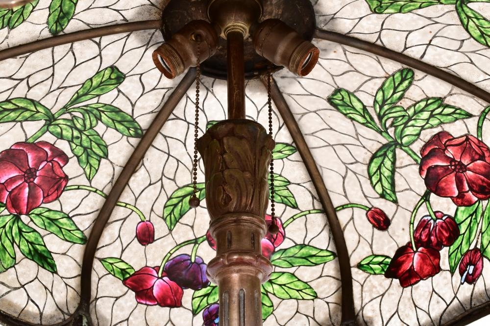 A tall floor lamp with a stained-glass floral shade and an ornate dark metal base.