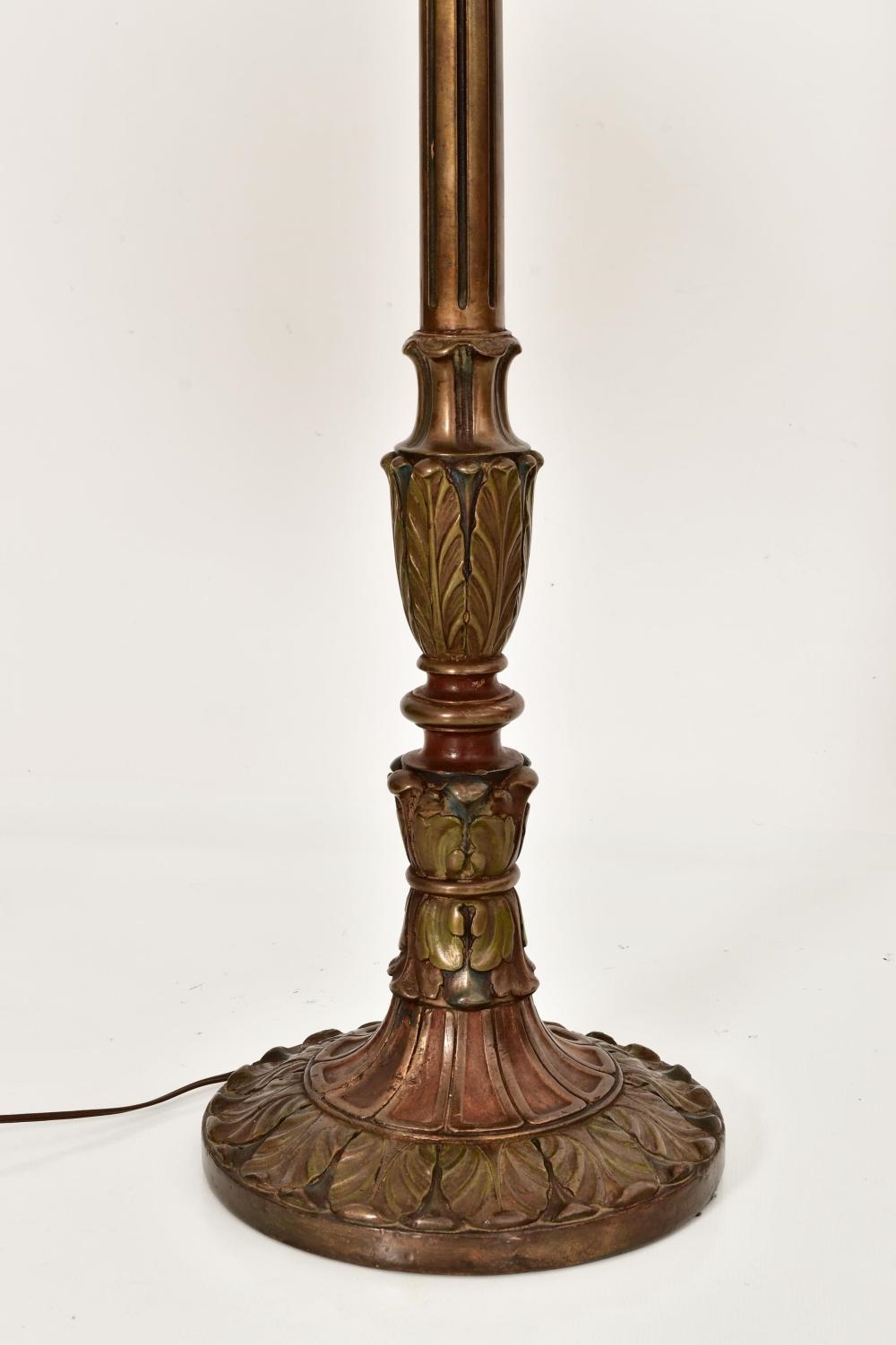 A tall floor lamp with a stained-glass floral shade and an ornate dark metal base.