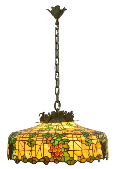 A stained glass pendant lamp featuring a grapevine motif and warm amber tones.