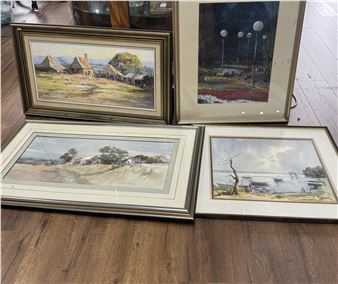A collection of four framed landscape paintings displayed on a wooden floor.