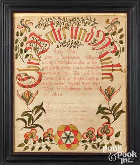 A framed historical document featuring ornate red and gold calligraphy surrounded by floral borders.