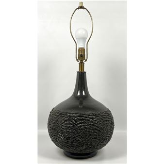 A modern table lamp featuring a textured dark base and brass hardware.