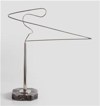 A sleek metal sculpture featuring a twisted wire form resting on a polished stone base.