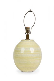 A ceramic table lamp with a pale yellow, horizontally striped base and a brass socket attached to a wire frame.