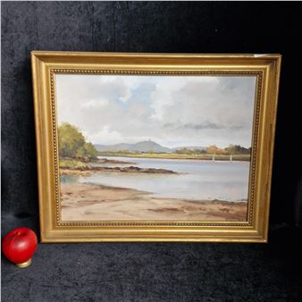 A framed landscape painting of a coastal scene with distant hills and calm water.