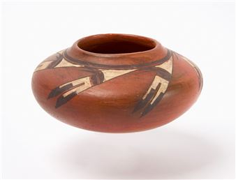 A small, reddish-brown ceramic vessel featuring bold geometric patterns in black and cream.