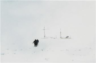 A desolate snowy landscape featuring two small figures and distant communication towers.
