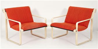 A pair of modern armchairs with orange upholstery and light-colored tubular frames.