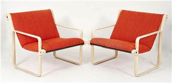 A pair of modern lounge chairs featuring light wooden frames and vibrant red upholstery.