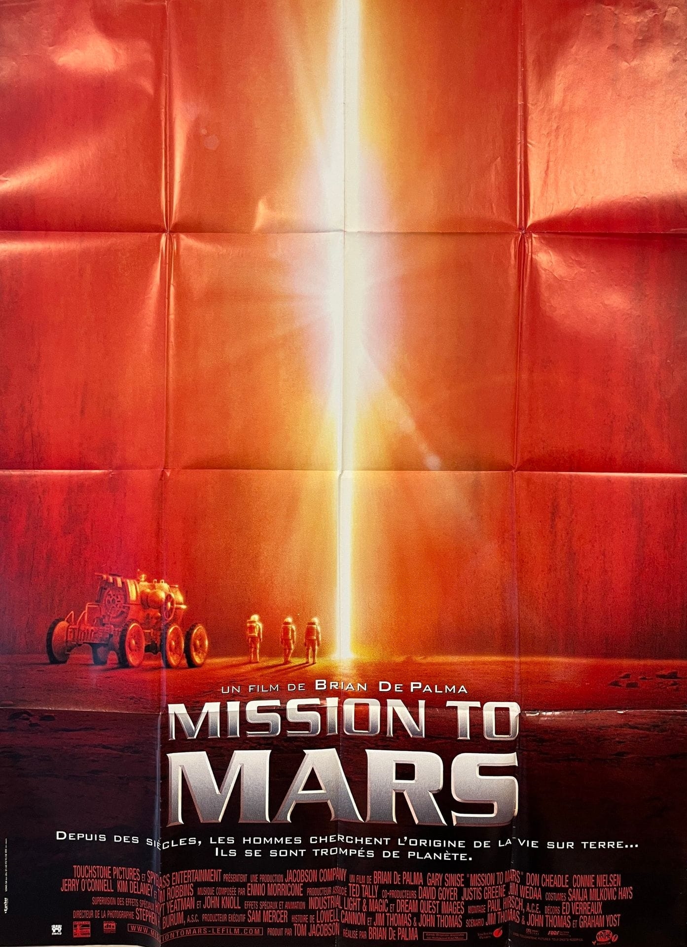 A dramatic poster featuring a bright light beam piercing through a red, metallic surface.
