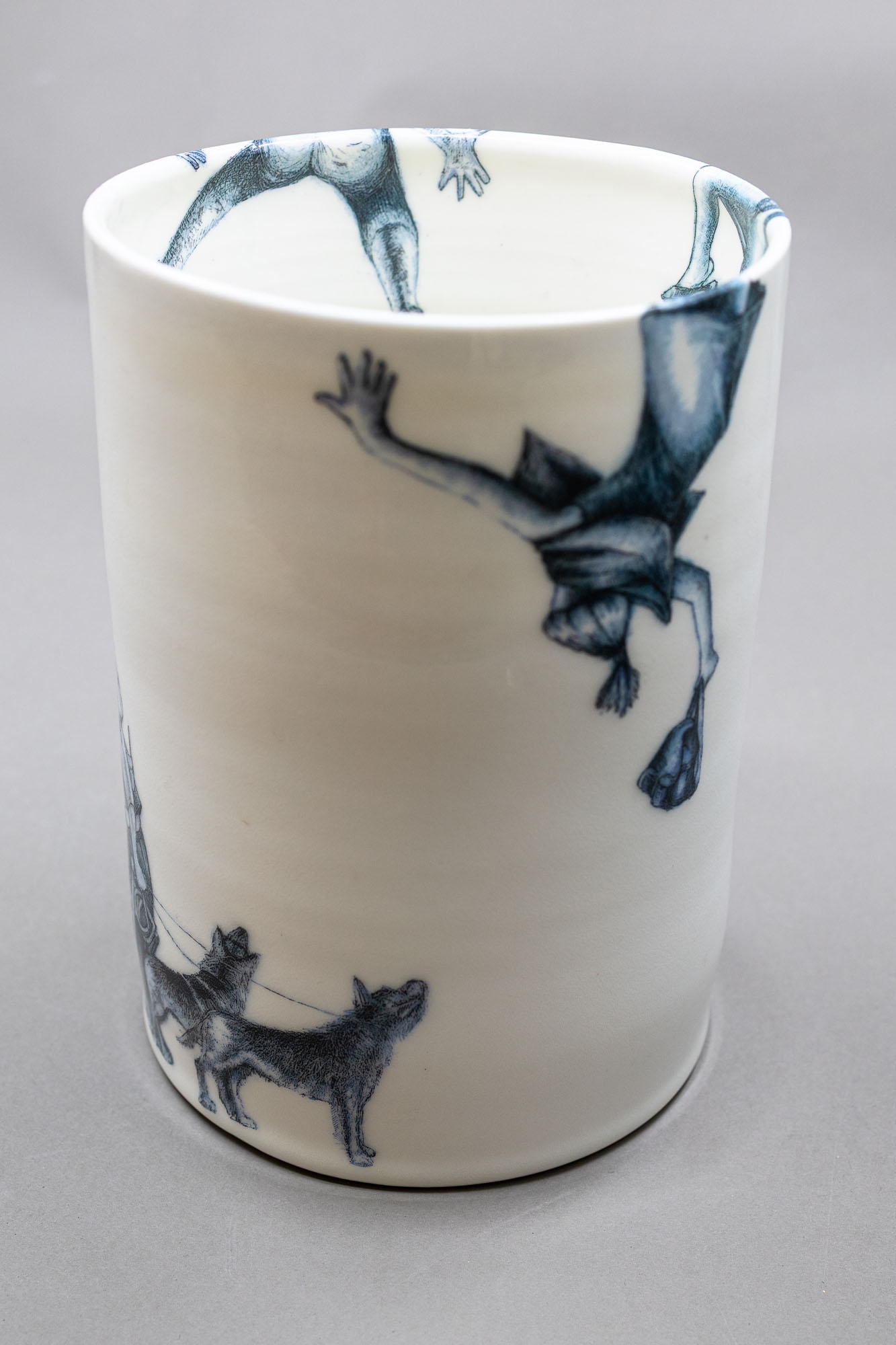 A white ceramic cup featuring a blue illustration of a figure with a dog and the text 'over the wall'.