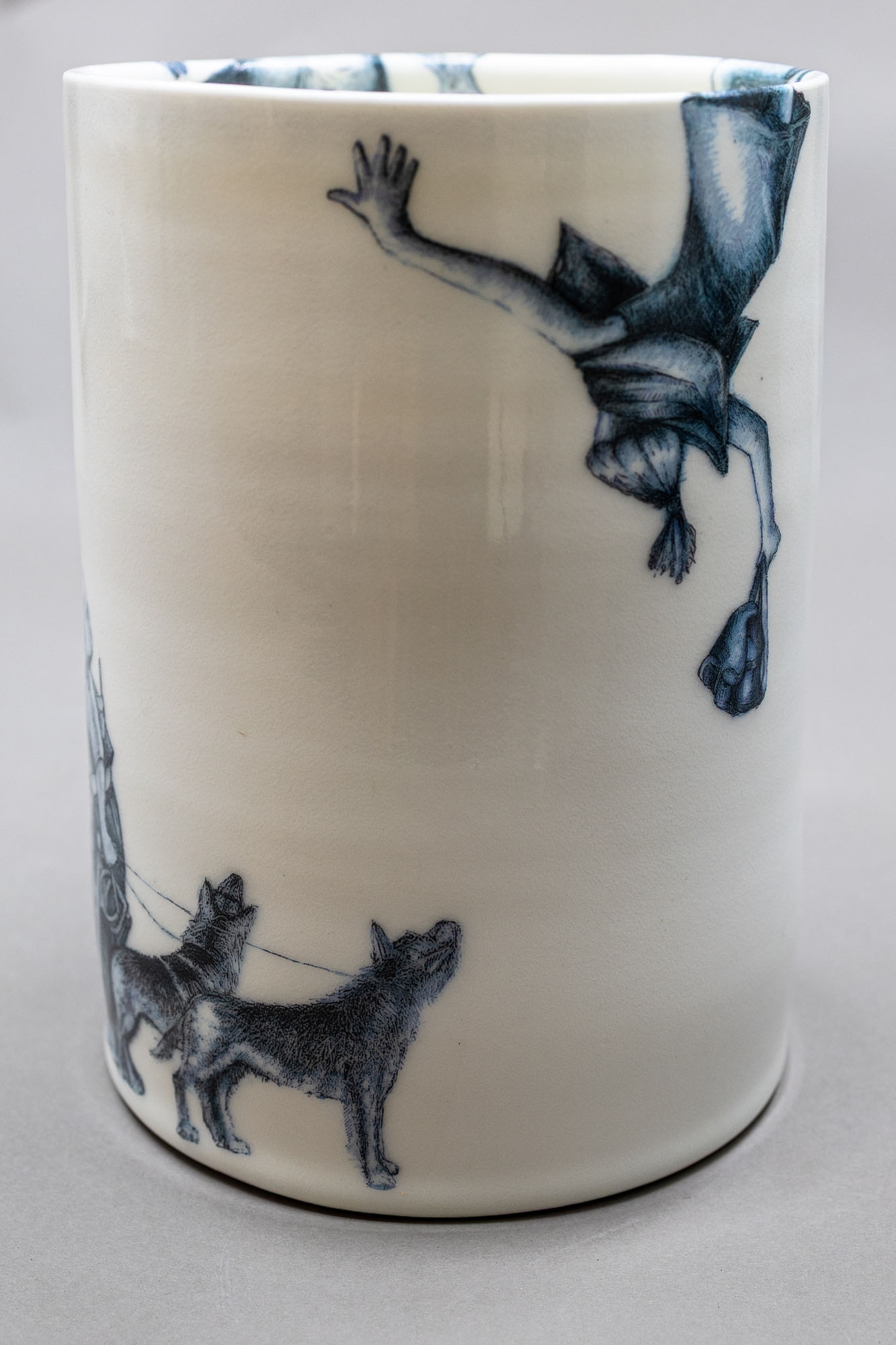 A white ceramic cup featuring a blue illustration of a figure with a dog and the text 'over the wall'.