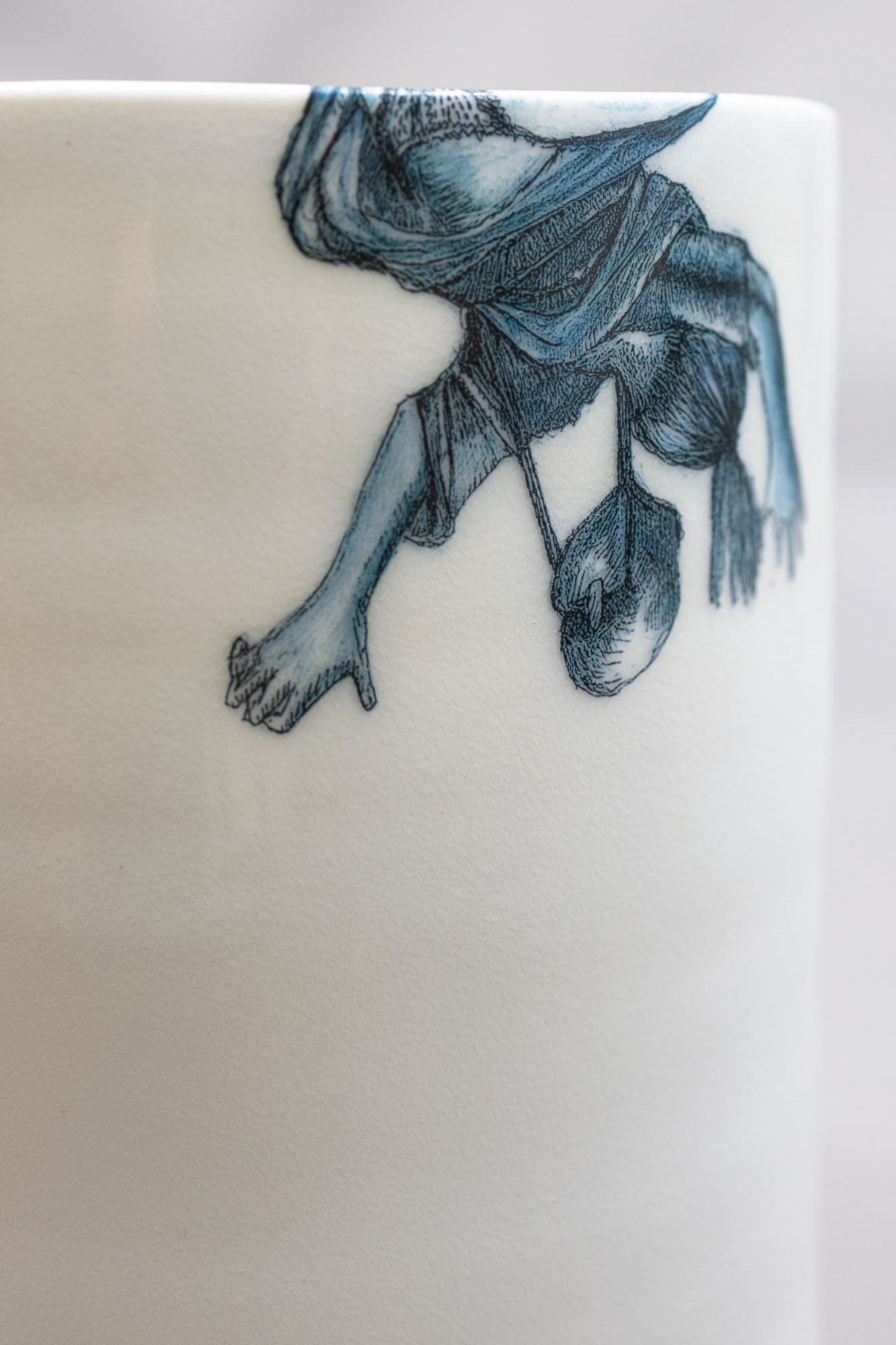 A white ceramic cup featuring a blue illustration of a figure with a dog and the text 'over the wall'.