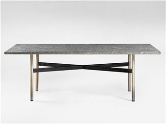 A modern dining table with a speckled stone top and crossed metal legs.