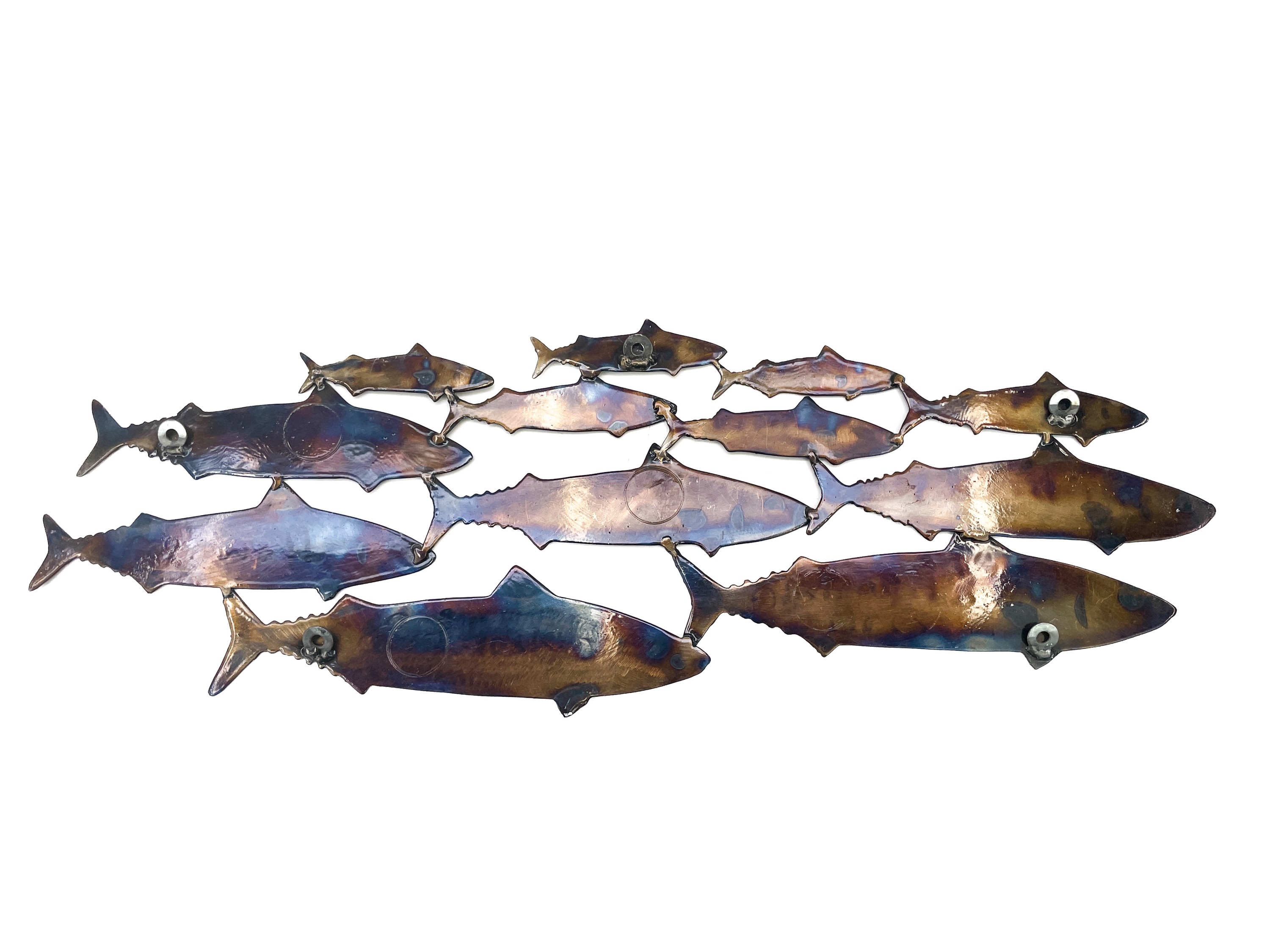 A metal wall art piece featuring a school of fish in shades of blue and brown.