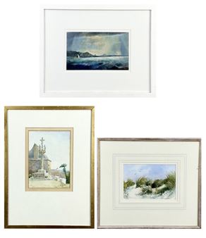 A collection of three framed watercolor paintings depicting coastal landscapes and a stone cross.