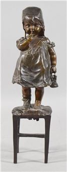 A small bronze sculpture of a child standing on a miniature stool.