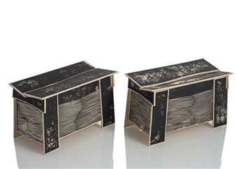 A pair of small, box-like sculptures with textured black tops and striped sides.