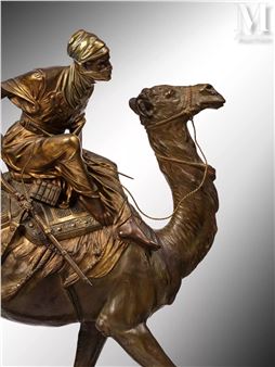 A bronze sculpture of a figure riding a camel, rendered in realistic detail with warm metallic tones.