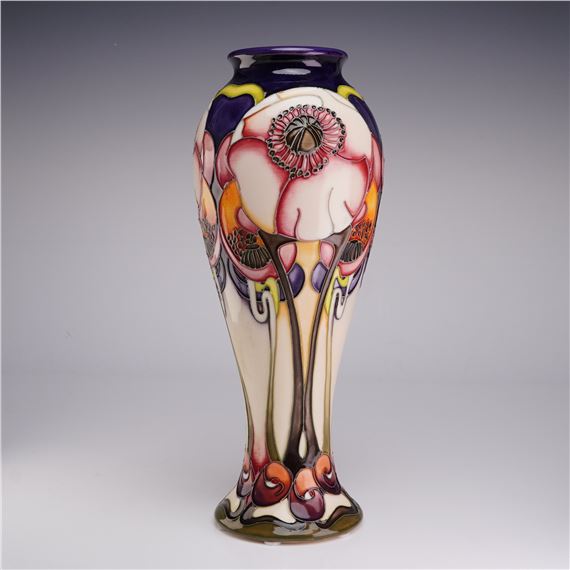 A tall ceramic vase featuring stylized floral patterns in pink, purple, and yellow against a cream background.