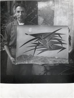 A black-and-white photograph of a person holding an abstract drawing with sharp geometric forms.