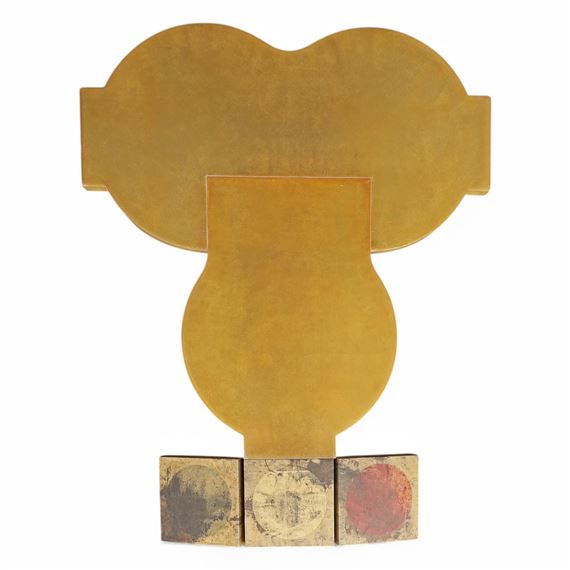 A golden abstract sculpture with a rounded top and three textured base blocks.
