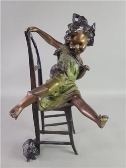 A whimsical bronze sculpture of a child figure lounging on a chair with a small animal companion.