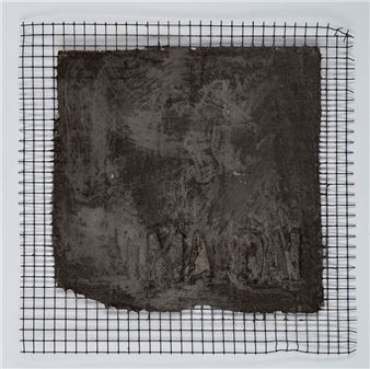 A dark, textured square block rests on a wire grid against a plain background.