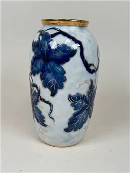 A glossy ceramic vase featuring a blue and white floral pattern with gold accents.